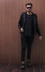 a man is standing in a black leather jacket and jeans