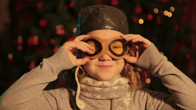 the girl in the flying helmet the pilot wears glasses. she is at home in front of the tree