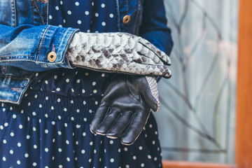 Woman hands with black and white fashionable snakeskin python gloves. Outdoors.
