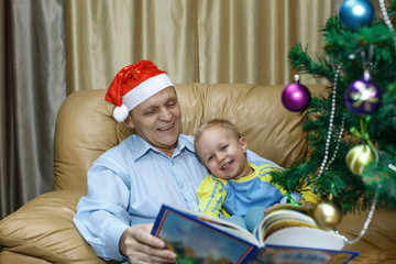 Fototapeta na wymiar grandfather and grandson read a Christmas fairy tale