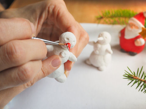 Artist is working in an atelier. Art and small sculpture snowman. Preparing for Christmas.

