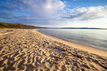 Summer Day At The Beach Background. Warm sunny summer day on the shore of Lake Superior with a wide sandy beach and blue water horizon. Horizontal orientation wide angle with copy space.