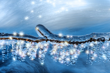 Ein Zweig mit dicken Eiszapfen hängt am Fluss