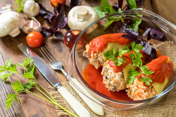 Yummy looking cooked stuffed pepper served in a transparent glass pot on a wooden table