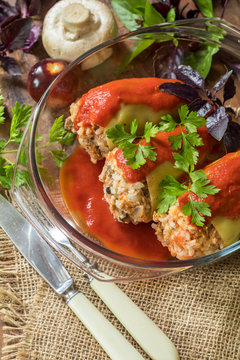 Yummy looking cooked stuffed pepper served in a transparent glass pot on a wooden table