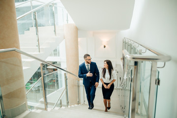 Businessman and Business woman walking up stairs with bags to office.