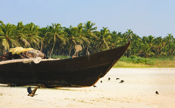 Traditional fishing boat on palm trees background, Cavelossim Beach in South Goa, India