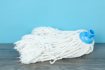 A cotton  head of classic mop on  wooden floor against blue wall