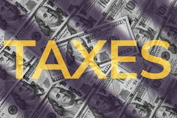 Taxes word on hundreds dollars of USA background