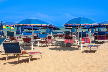 Adriatic Sea coast view. Seashore of Italy, summer umbrellas on sandy beach with clouds on horizon.