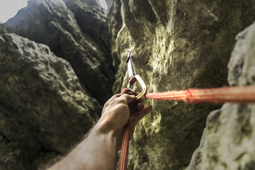 The climber's hand clicks the rope in carbine. Rock climbing