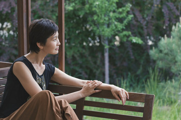 Girl sits on a bench and looks thoughtfully into the distance. Woman dreams. Relax.