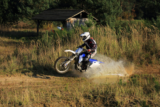 Enduro, motocyklista na motorze crossowym w kałuży.