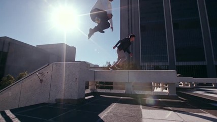 Free runners in action outdoors in city. Two young men doing parkour tricking and freerunning in the city. Jumping from an obstacle and running.  - Powered by Adobe