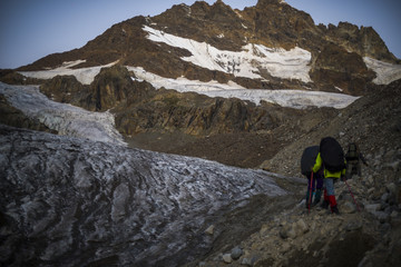 A group of hiking tourists go along the glacier to the mountain pass. The weather facilitates complex movement in the high-mountainous area. Travelling in the Caucasian Mountains in Georgia