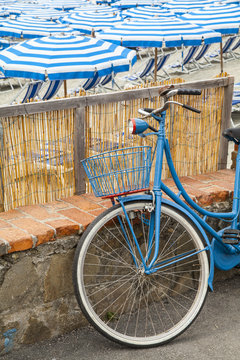 Bicicleta azul al lado de las sombrillas de la playa con mismo color azul