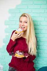 Beautiful young woman enjoying in delicious glazed and decorated donuts. 