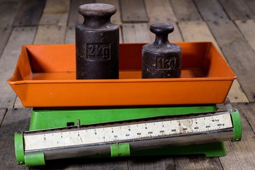 Old weight and weights on a wooden table. Old used kitchen scale with old scale and kilogram weight...