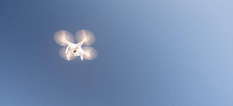 White UAV Quadcopter Drone in Flight Blue Sky