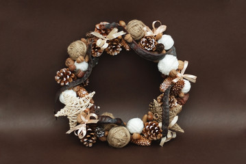 Christmas Rustic Wreath of Cones and Pinecones with Cotton Branchs Isolated on Brown Background.