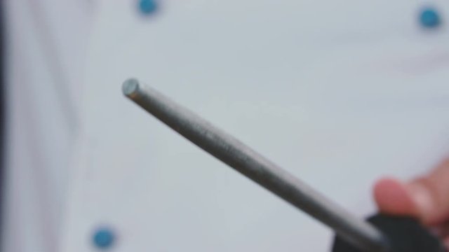 Close-up of chef at restaurant sharpens knife with steel