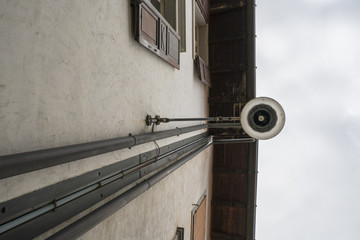 A street lamp on the wall of a house in the historic center of Venzone, Friuli, Italy	
