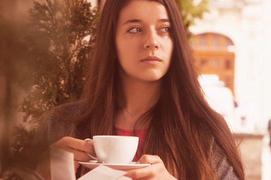 Beautiful young woman drinks coffee and reading a book. (relax, romance, poetry, rest)