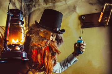 Bearded man wearing black hat and vest with the lantern. Medicine man in Dickens style.