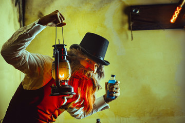 Bearded man wearing black hat and vest with the lantern. Medicine man in Dickens style. - obrazy, fototapety, plakaty