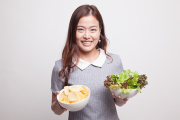 Young Asian woman with potato chips and salad.