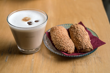Cup of Hot Coffee with bread cookies served on wooden table