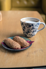 Cup of Hot Coffee with bread cookies served on wooden table