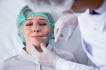 Naklejka premium Plastic surgeon preparing for operation on woman face
