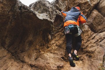 Hipster - climber at the age of climbing up a beautiful rock without insurance and helmet