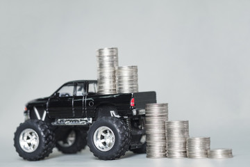 Miniature car pickup truck with stacks of coins on grey background with copy space, banking savings money and business finance concept. © pookpiik