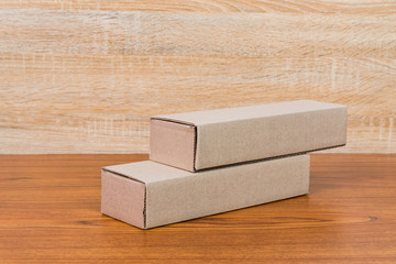 Empty Package brown cardboard box for long items on wooden table with copy space.