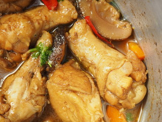 Close up chicken wing sticks stewed boiled with Shiitake mushroom and carrot, decorated with parsley coriander leaf, in aluminum pot, as Thai local traditional homemade food