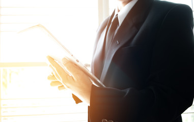 Businessman using tablet with suit standing near windows for online banking payment on network technology internet by mobile smartphone sync app, Technology Concept.