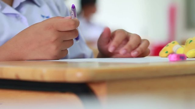 Students holding pencil eraser while taking exams, examination room, writing answer optical form in high school classroom, view of having test in class on seat rows, Education  literacy concept.