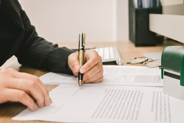 Business man signing agreement paper on wooden table, signing concept