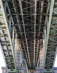 A view from below on the design of the bridge. Concrete piles and iron slabs.