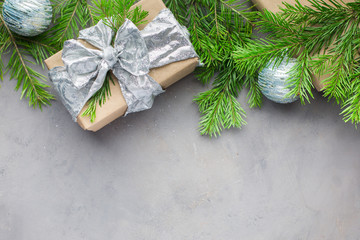 Christmas background in gray-blue colors with gifts wrapped in kraft paper, with ribbons, with glass Christmas-tree balls and xmas tree. Flat lay, top view