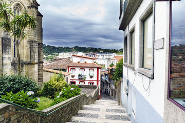 Street formed by stone stairs with a very colorful house and a sky with clouds threatening rain in...