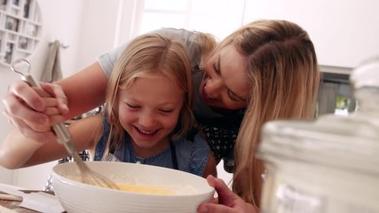 Happy young family having fun in kitchen. Playful mother and daughter in kitchen while preparing food.
 - Powered by Adobe