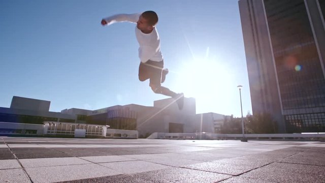 Parkour man jumping high and performing a flip. Urban man practicing parkour in urban space.