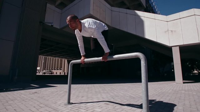 Man practices parkour and free running outdoors. Male free runner jumping over a railing performing parkour.