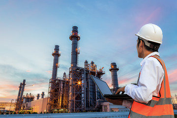  Engineering is use notebook check and  standing in front of oil refinery building structure in...