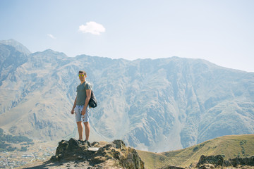 Fototapeta premium Guy with a travel backpack on the top of a boulder
