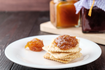 Crackers with orange jam on wooden background