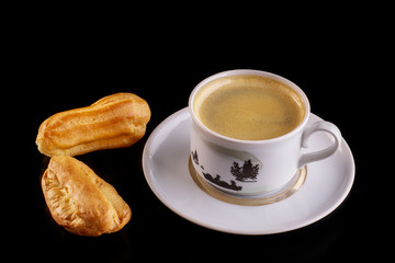 Cake eclair with chocolate icing, cup of coffee, chocolate, on a black background